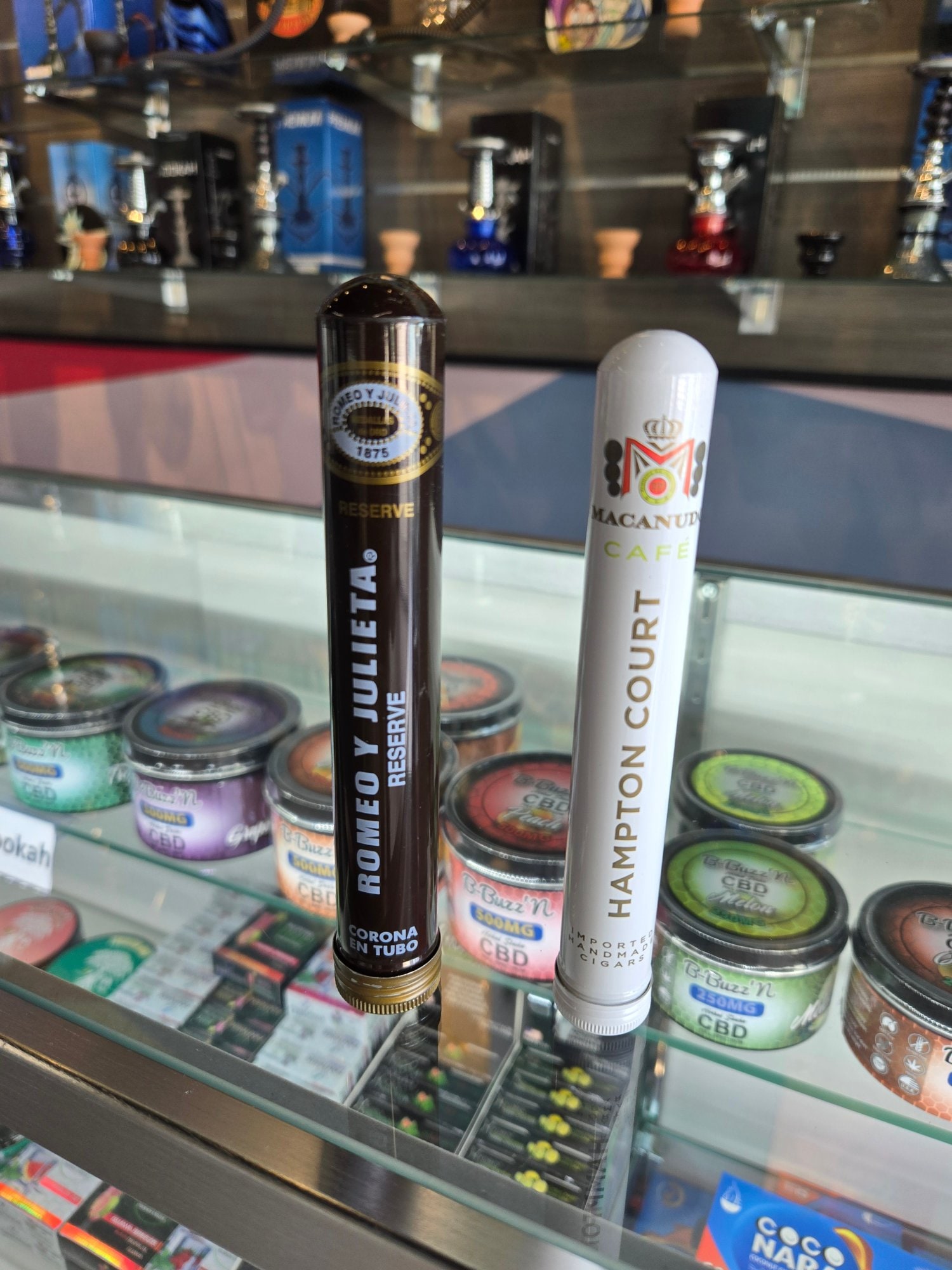 Romeo y Julieta Reserve and Macanudo Cafe Hampton Court tubes held above the counter at the shop.