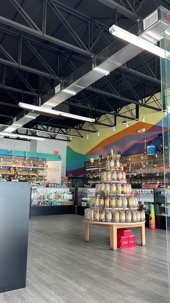 Inside the shop: a display of incense jars on a round table in front of the painted geometric wall, with the counter beyond.