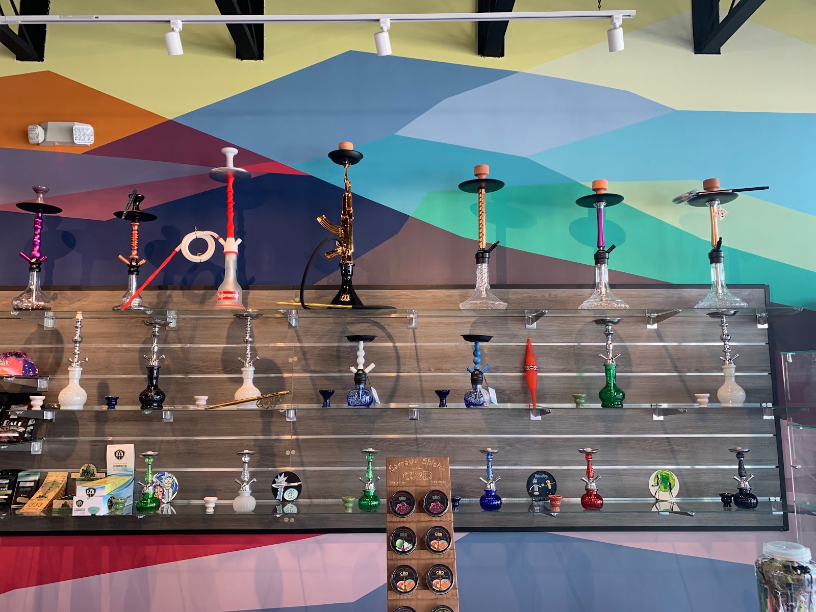 A wall of hookahs lined up against the shop's painted geometric wall.