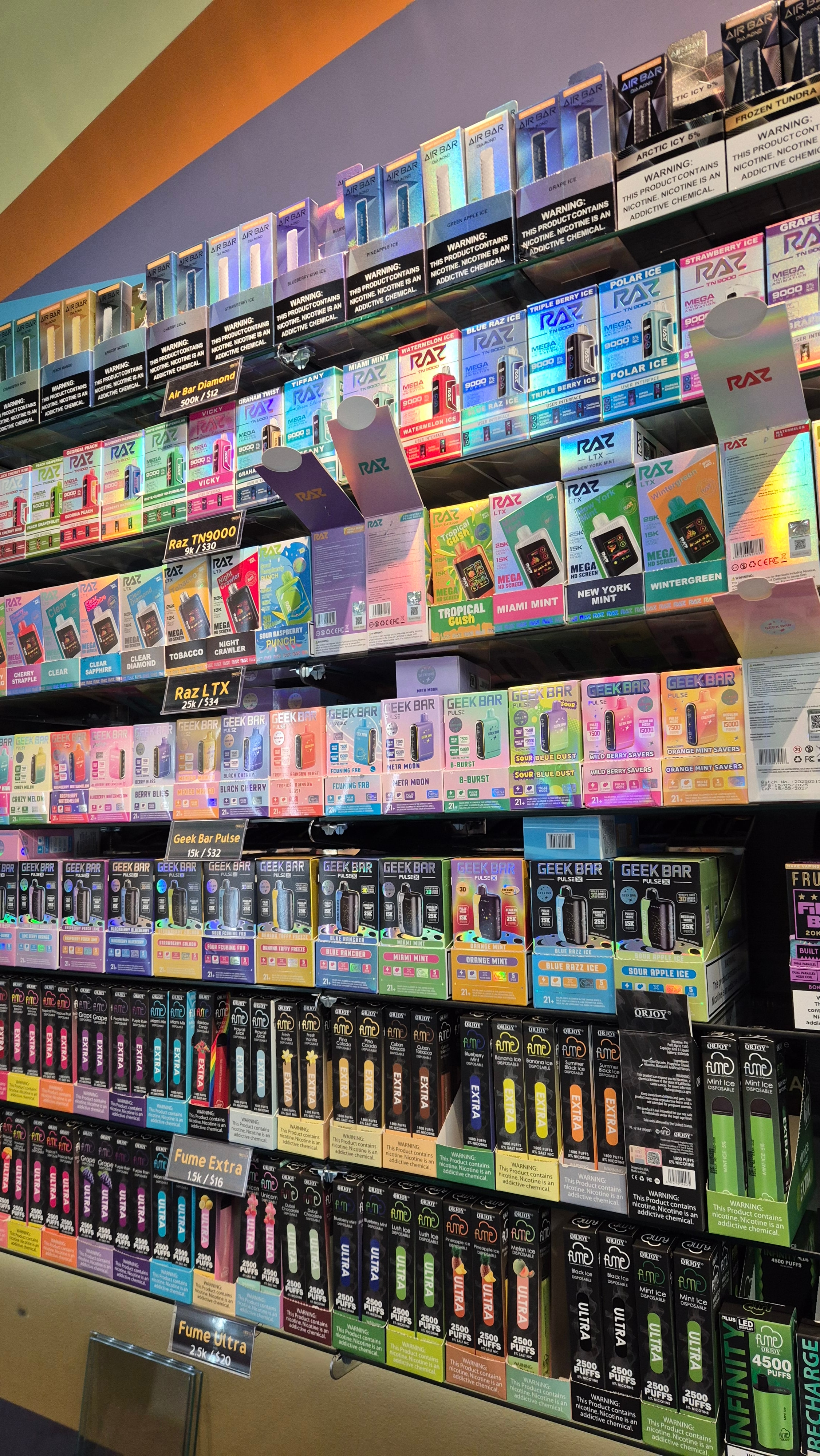 The disposables wall at the counter: Air Bar Diamond, RAZ TN9000 and LTX, Geek Bar Pulse, Fume Extra and Fume Ultra stacked by flavor.