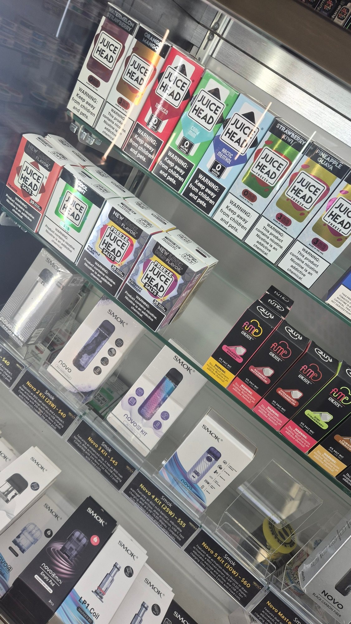 Bottles of Juice Head e-liquid on the shelf, 0MG and 3MG freebase above, 25MG and 35MG salt nic below.